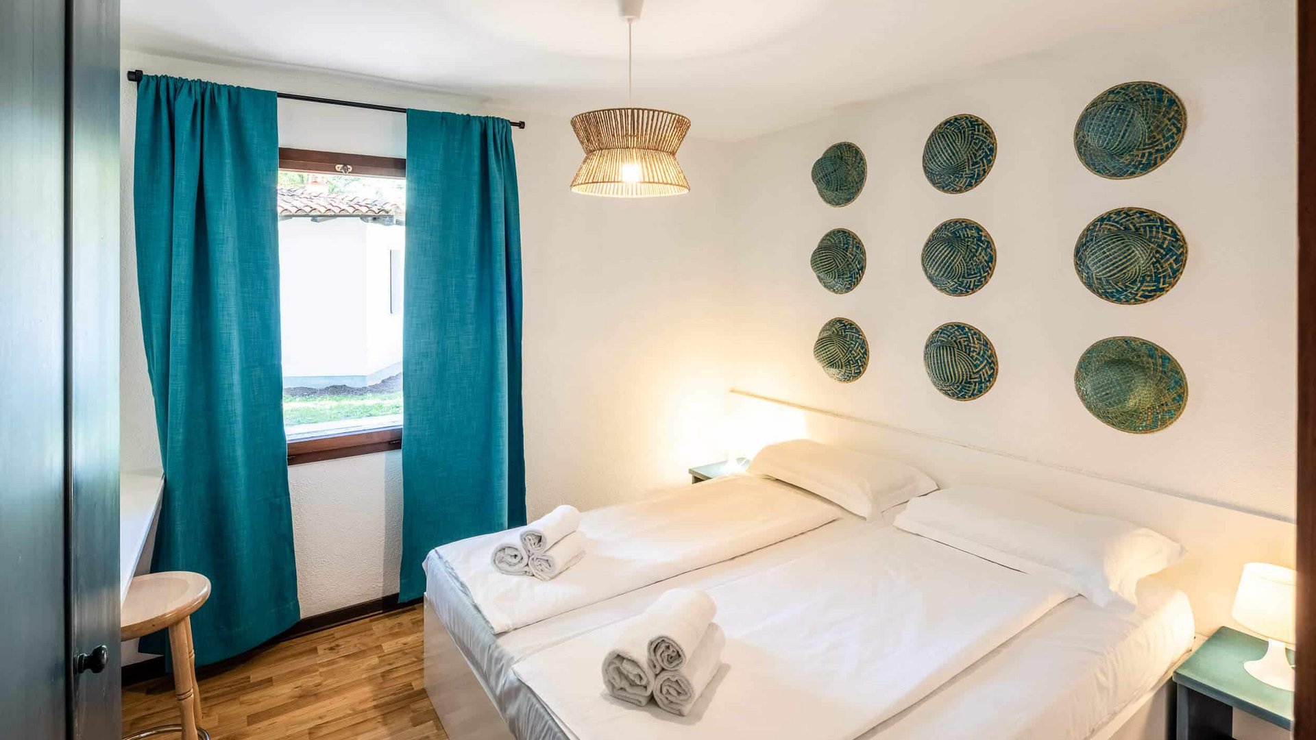 Small bedroom with two single beds, blue curtains, and decorative wall plates