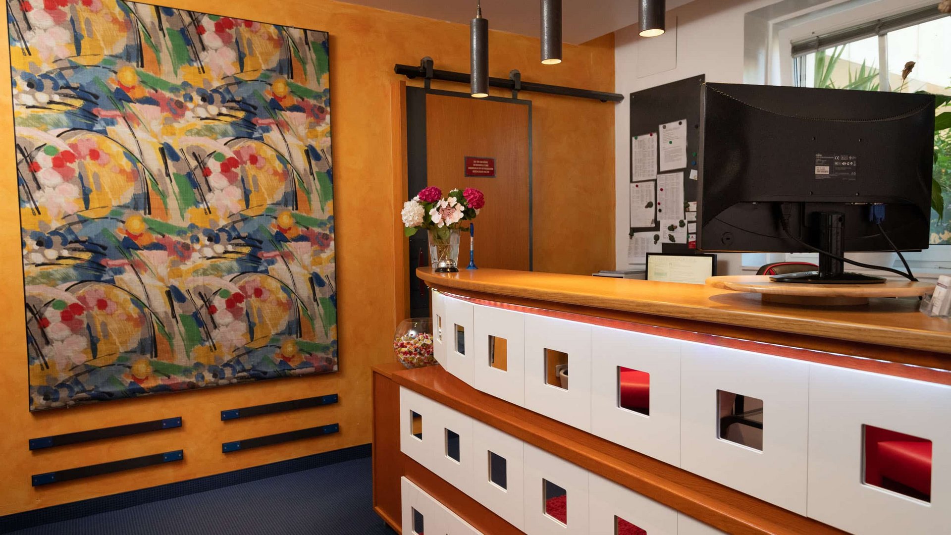 Modern reception desk with flowers and abstract painting on wall
