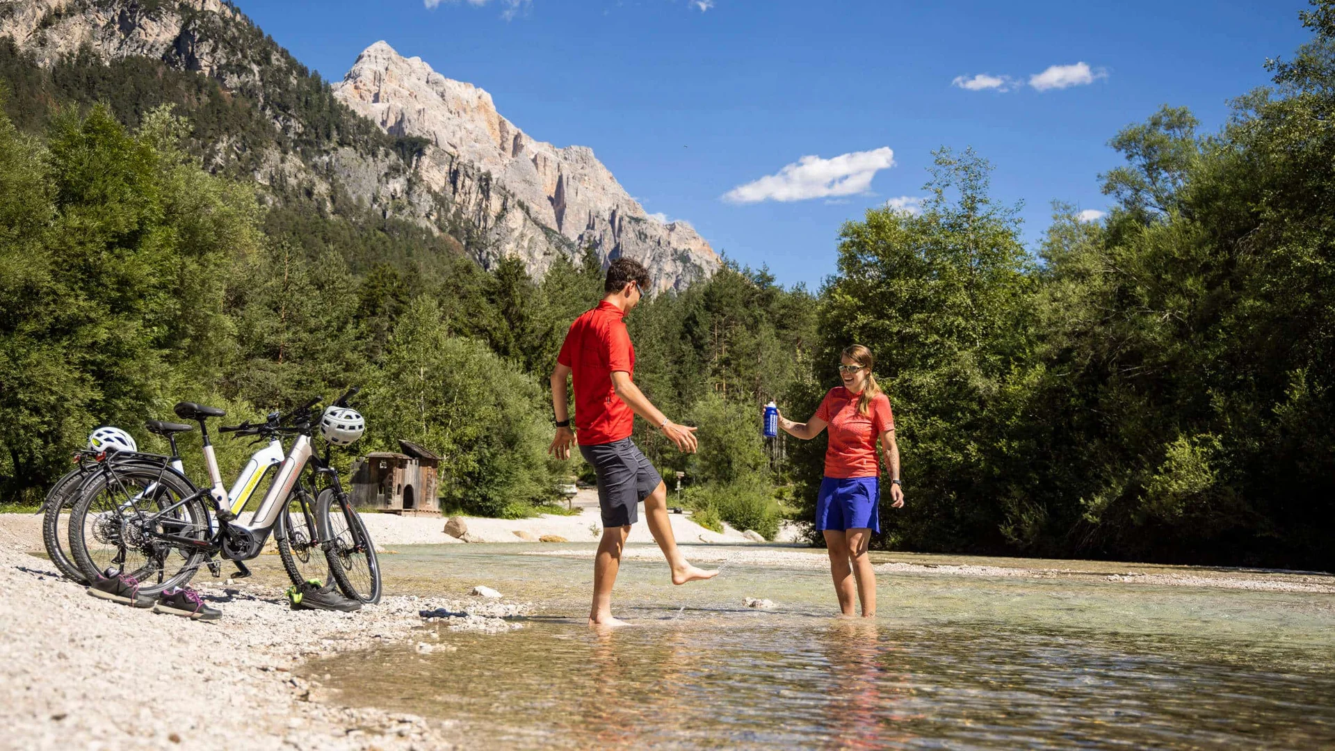 Zwei Radfahrer genießen Wasserpause in Berglandschaft am Flussufer