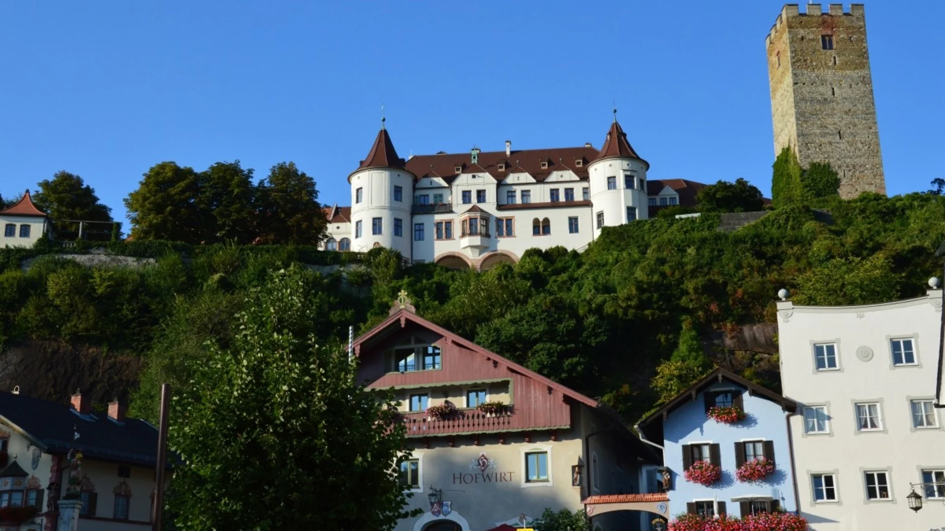 Historische Burg auf einem Hügel mit klassischer Architektur und bunten Häusern unten