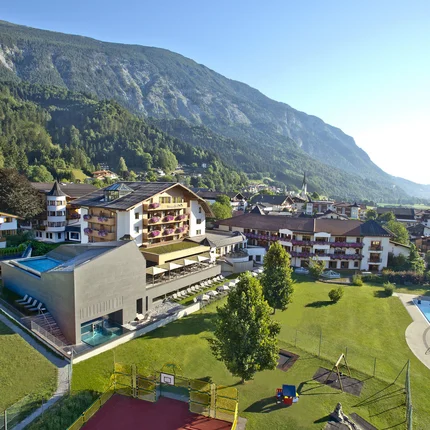 Hotel und Dorf in bergiger Landschaft mit Schwimmbad und Spielplatz