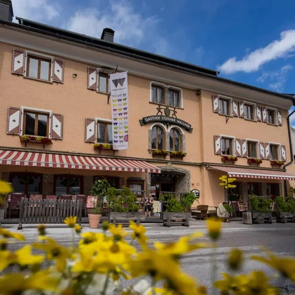Gasthof Steffner Wallner mit gelben Blumen im Vordergrund bei blauem Himmel