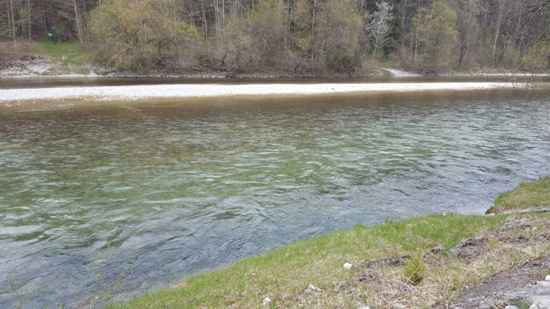 Fluss mit klarem Wasser, Kieselstrand und bewaldetem Ufer
