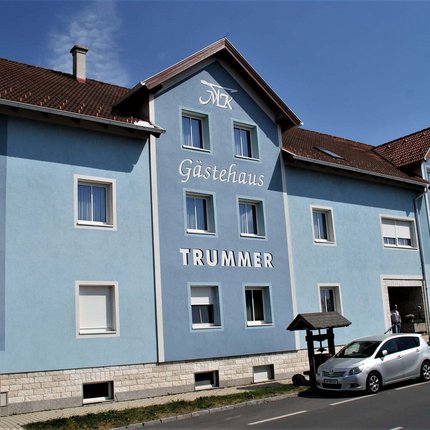 Blue guesthouse Trummer with cars parked outside on street