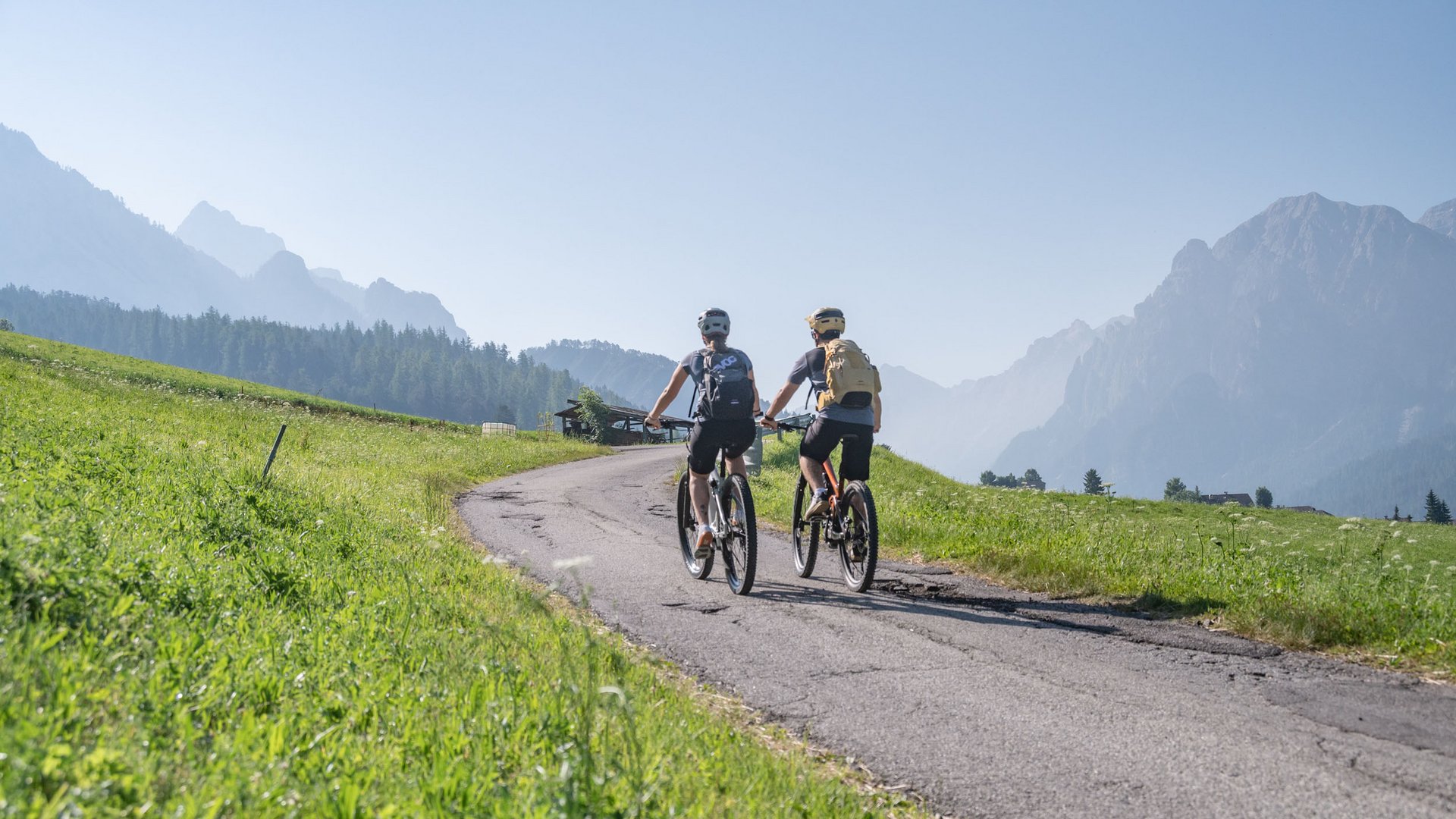 Two cyclists riding on a mountain road in sunny weather