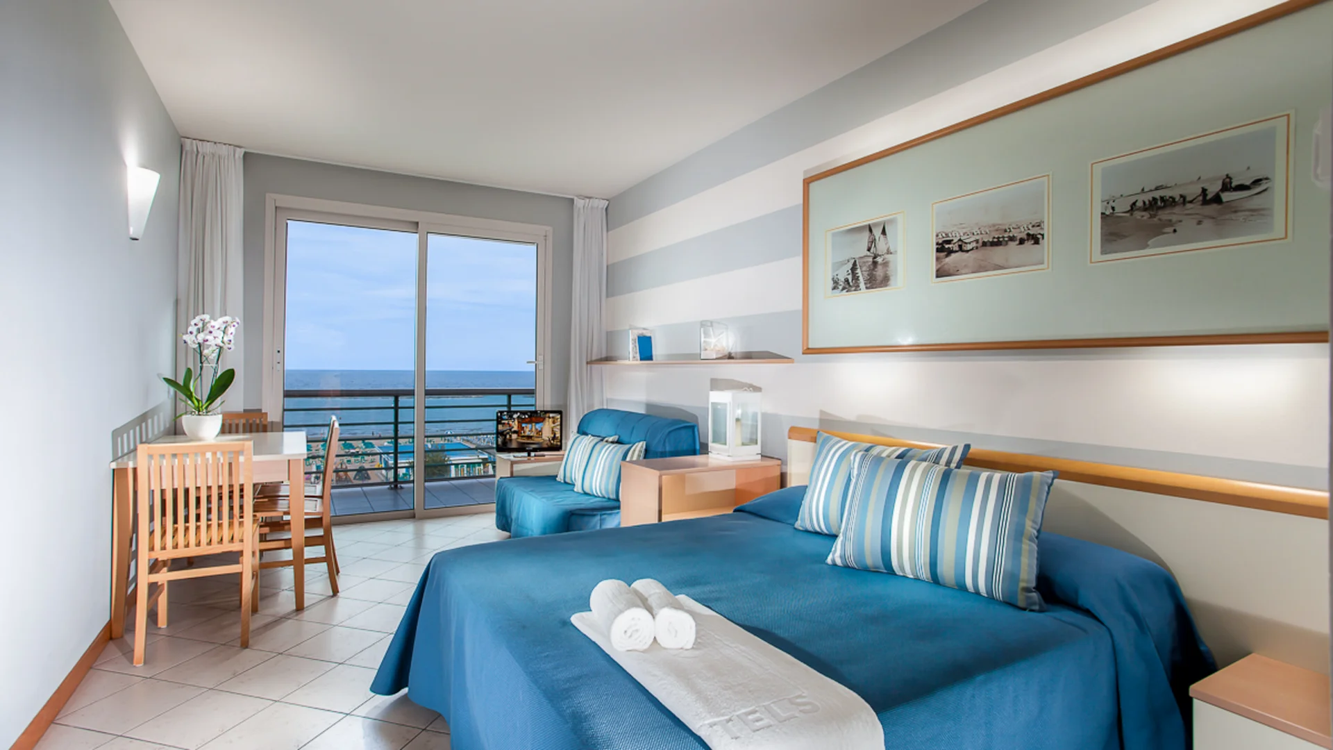 Hotel room with blue bed, balcony, and sea view