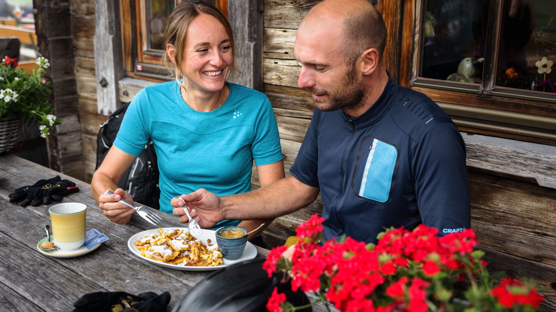 Couple eating cake and drinking coffee at wooden table outside cabin