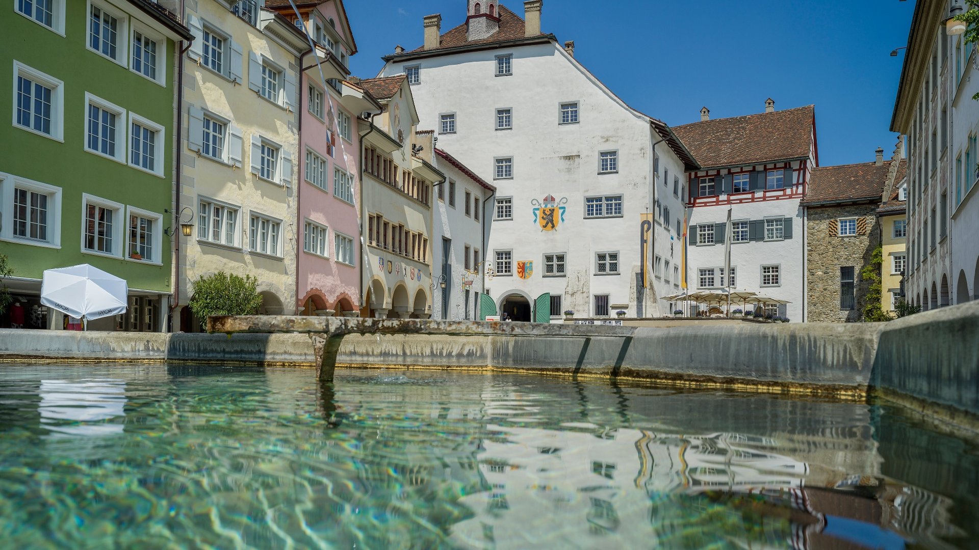 Historic buildings by clear water under a blue sky
