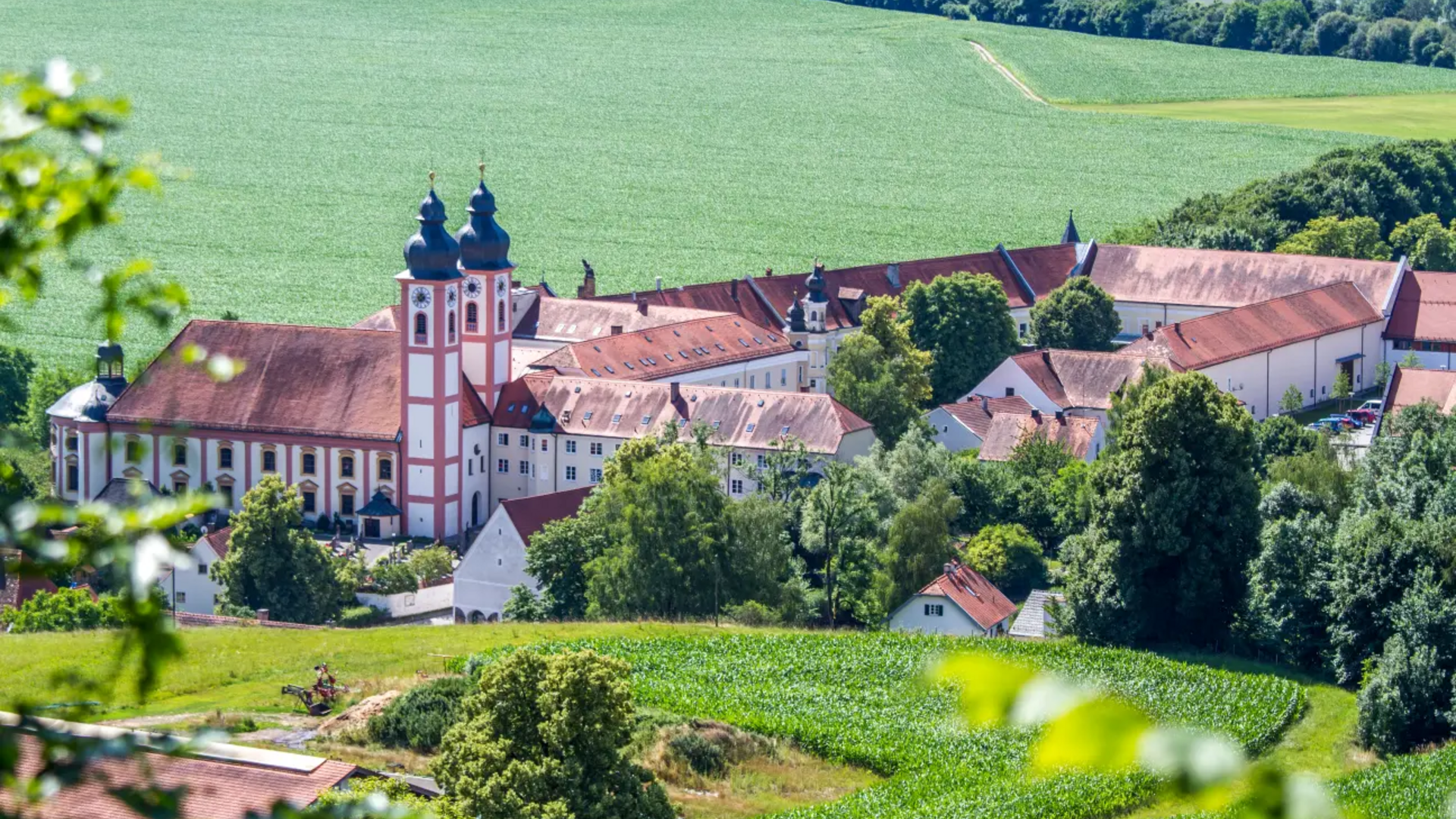 View of a large monastery with two church towers in a rural landscape