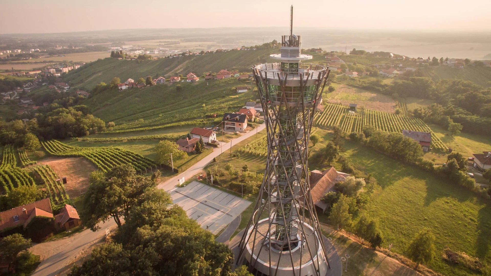 Uitkijktoren in groene heuvels met huizen tijdens zonsondergang