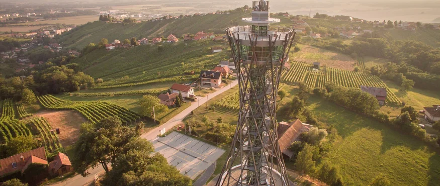 Uitkijktoren in groene heuvels met huizen tijdens zonsondergang
