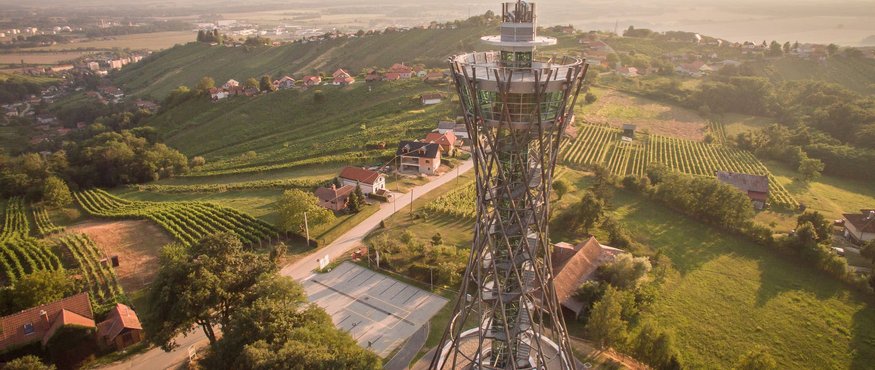 Observation tower in green hills with houses during sunset
