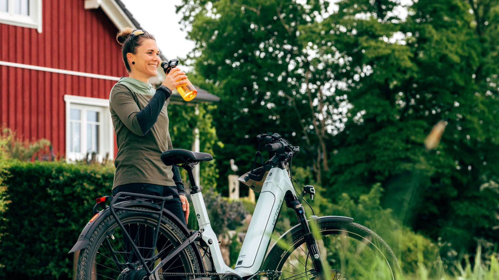 Victoria Woman drinking water next to her e-bike outdoors