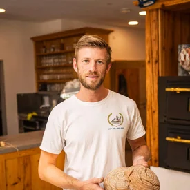 Man in bakkerij met twee versgebakken broden in handen