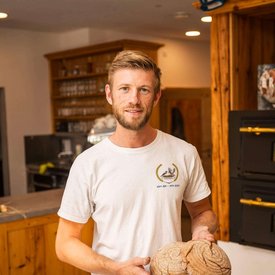 Man in bakery holding two freshly baked loaves of bread