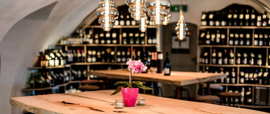 Rustikaler Holztisch mit Orchidee in Weinkeller mit Hängelampen