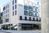 Collective enquiries © arte Hotel Kufstein Modern hotel building with outdoor seating and umbrellas