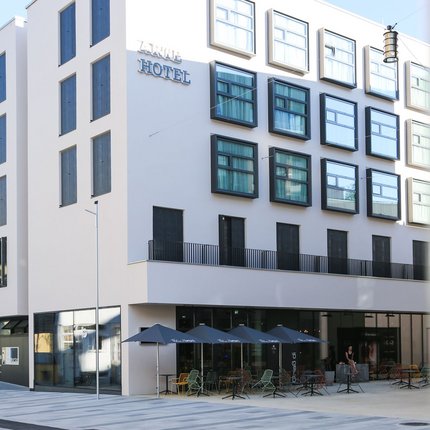 Modern hotel building with outdoor seating and umbrellas