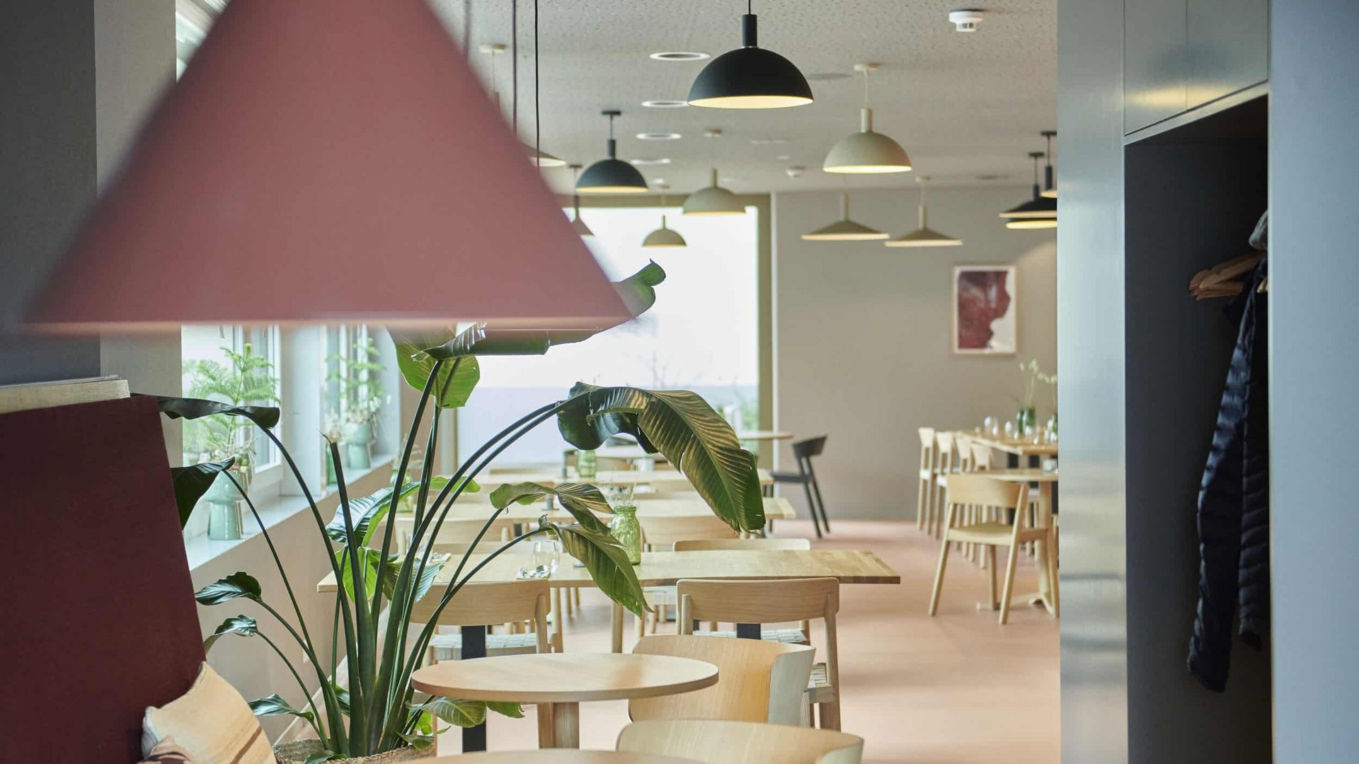 Modern bright dining area with small wooden tables and hanging lamps