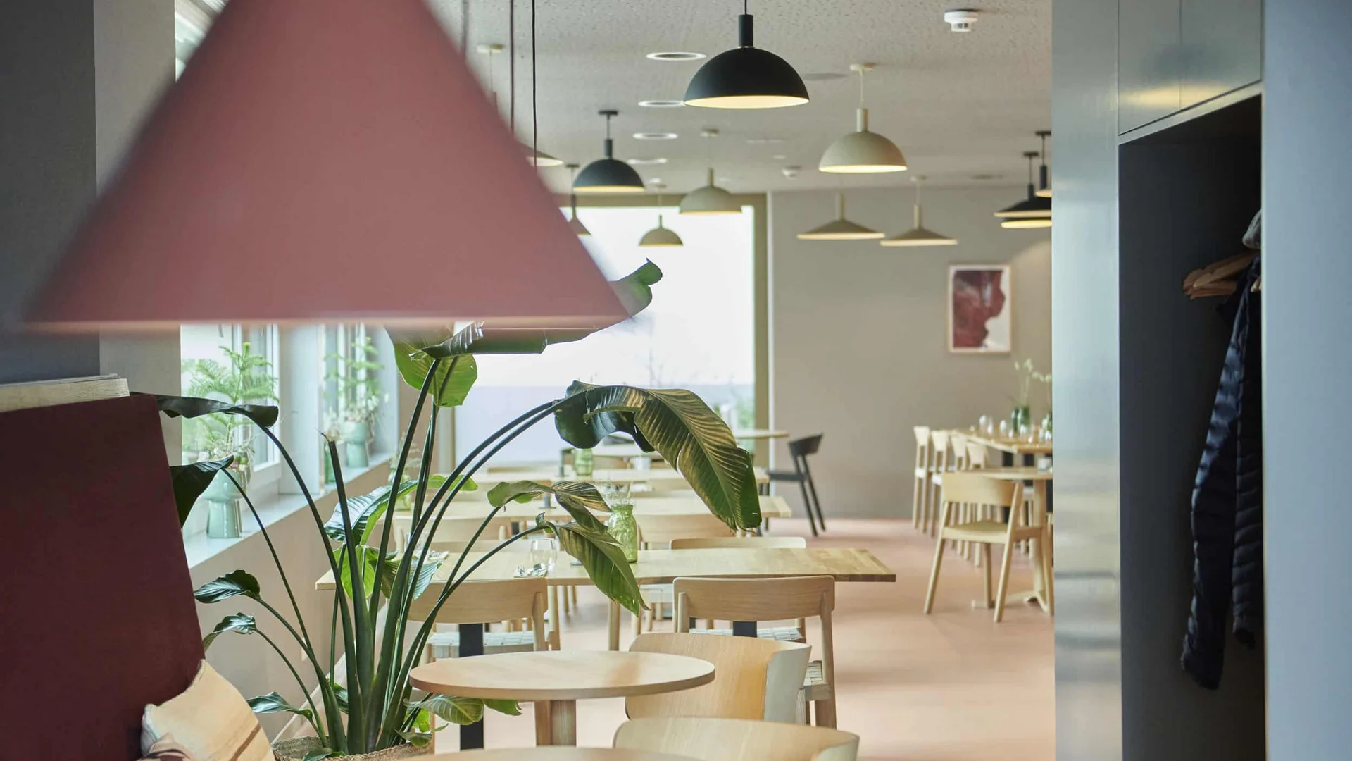 Modern bright dining area with small wooden tables and hanging lamps