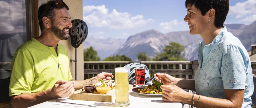 Ein Genuss-Radtag am Reschensee © Heiko Mandl Zwei Personen essen auf Terrasse mit Bergblick bei sonnigem Wetter