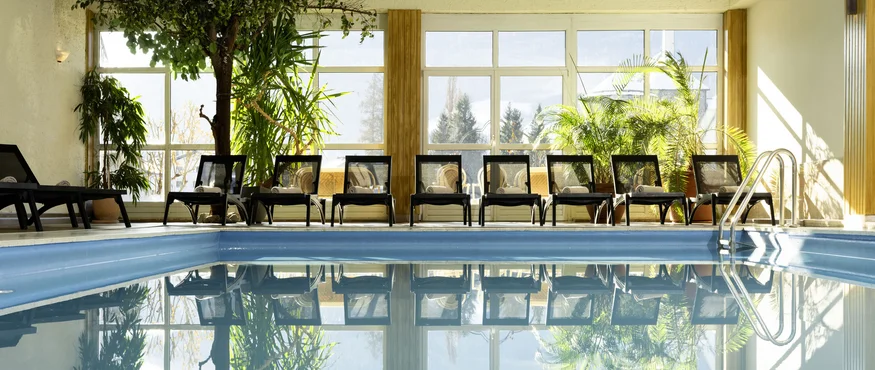 Indoor swimming pool with lounge chairs and large windows
