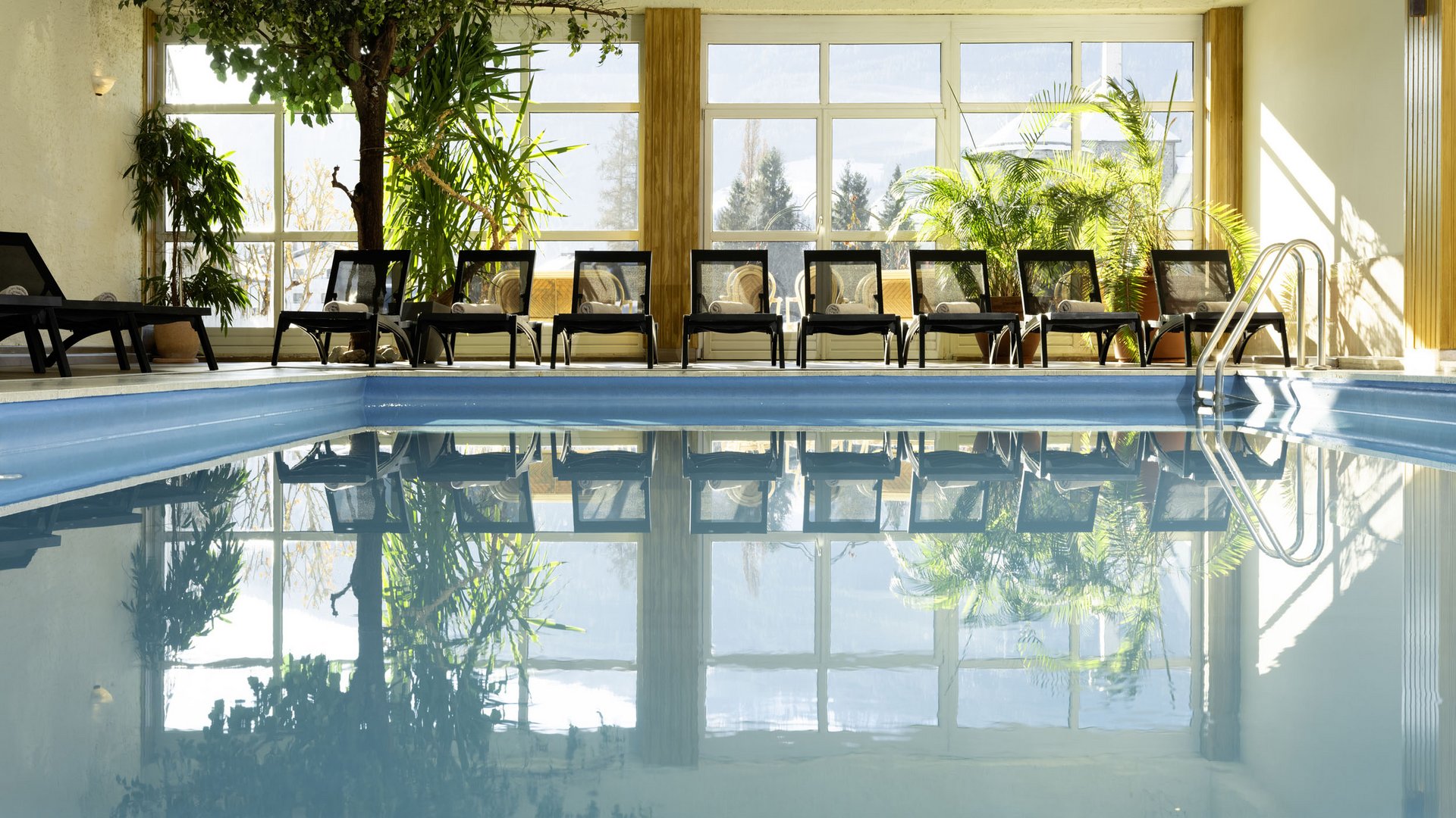 Indoor swimming pool with lounge chairs and large windows
