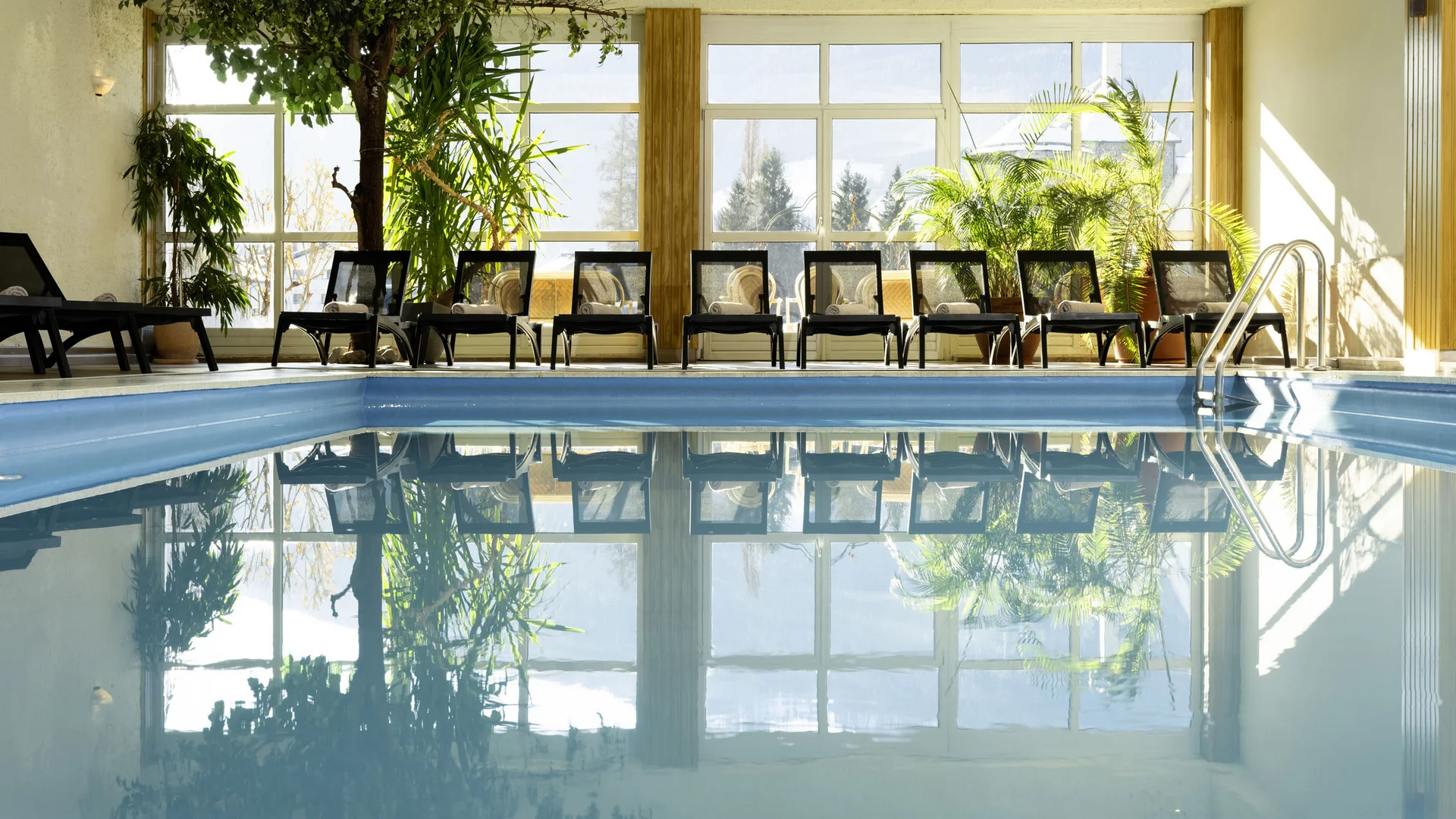 Indoor swimming pool with lounge chairs and large windows