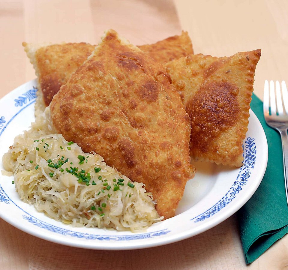 Plate with fried dumplings and sauerkraut beside fork on green napkin