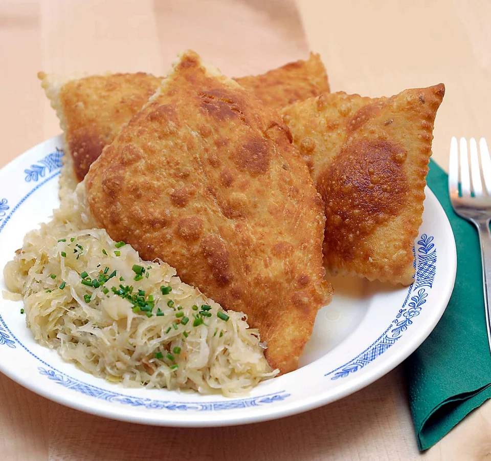 Bord met gebakken dumplings en zuurkool naast vork en groene servet