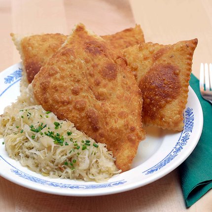 Plate with fried dumplings and sauerkraut beside fork on green napkin