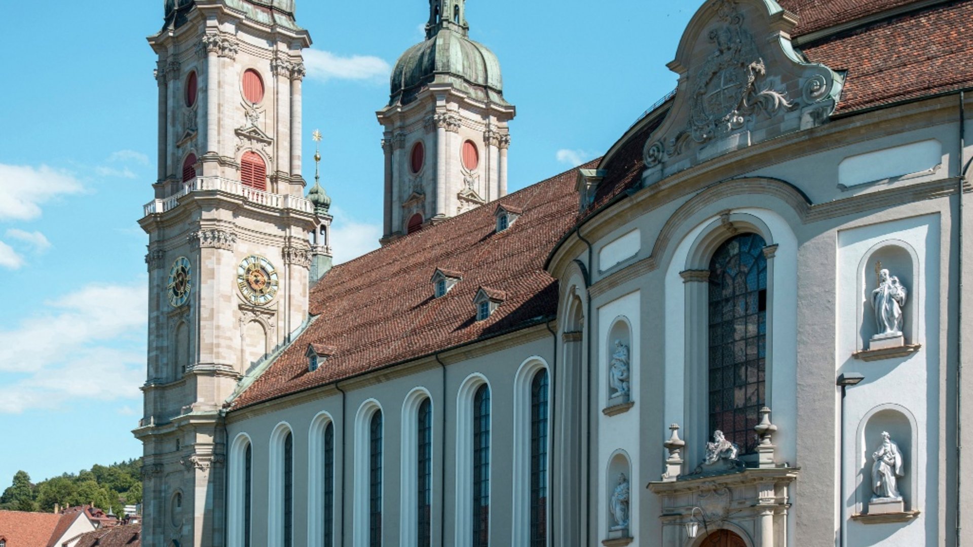 Two cyclists riding past a historic church under clear blue sky