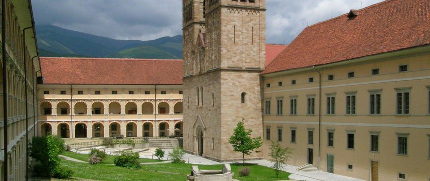 Monastery courtyard with twin church towers and mountains in background