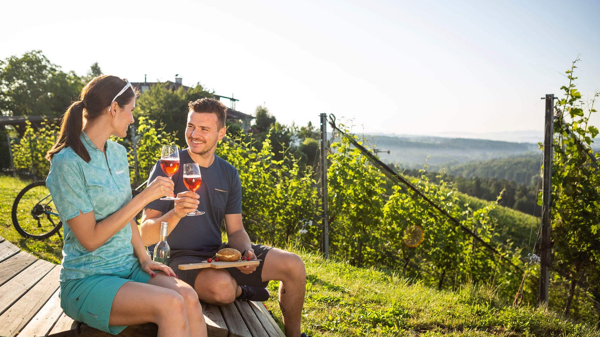 Couple drinking wine and enjoying snack in vineyard on sunny day