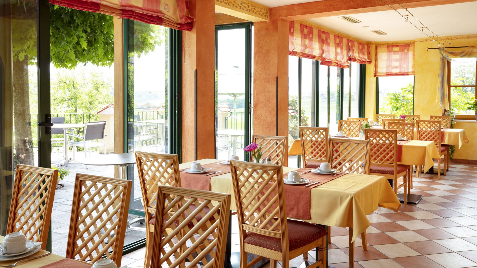 Bright restaurant with wooden tables and chairs, sunlit and welcoming