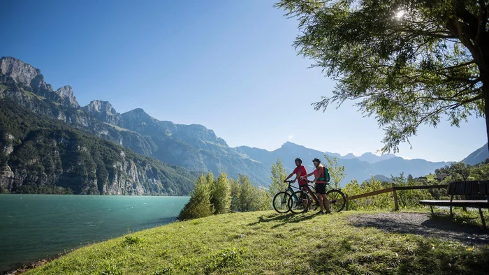 5 Punkte für Heidiland-Bucket List © Velontour Zwei Radfahrer genießen den Blick auf Bergsee und Berge bei sonnigem Wetter