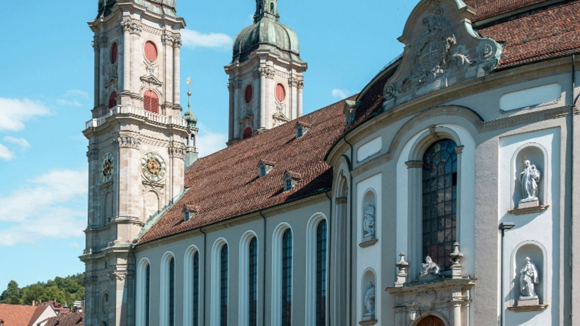Two cyclists riding past a large historic church on a sunny day