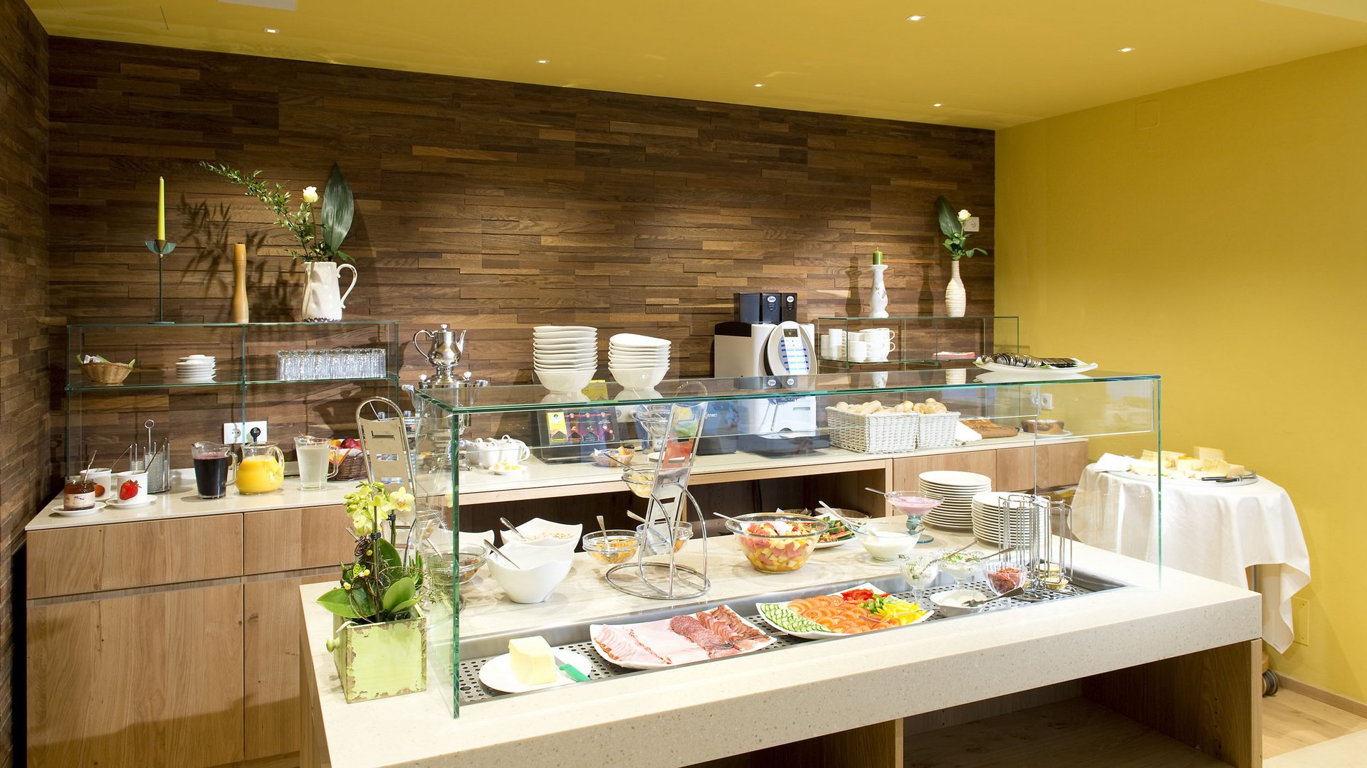 Buffet with cold cuts, cheese, fruit salad, and drinks in a modern room