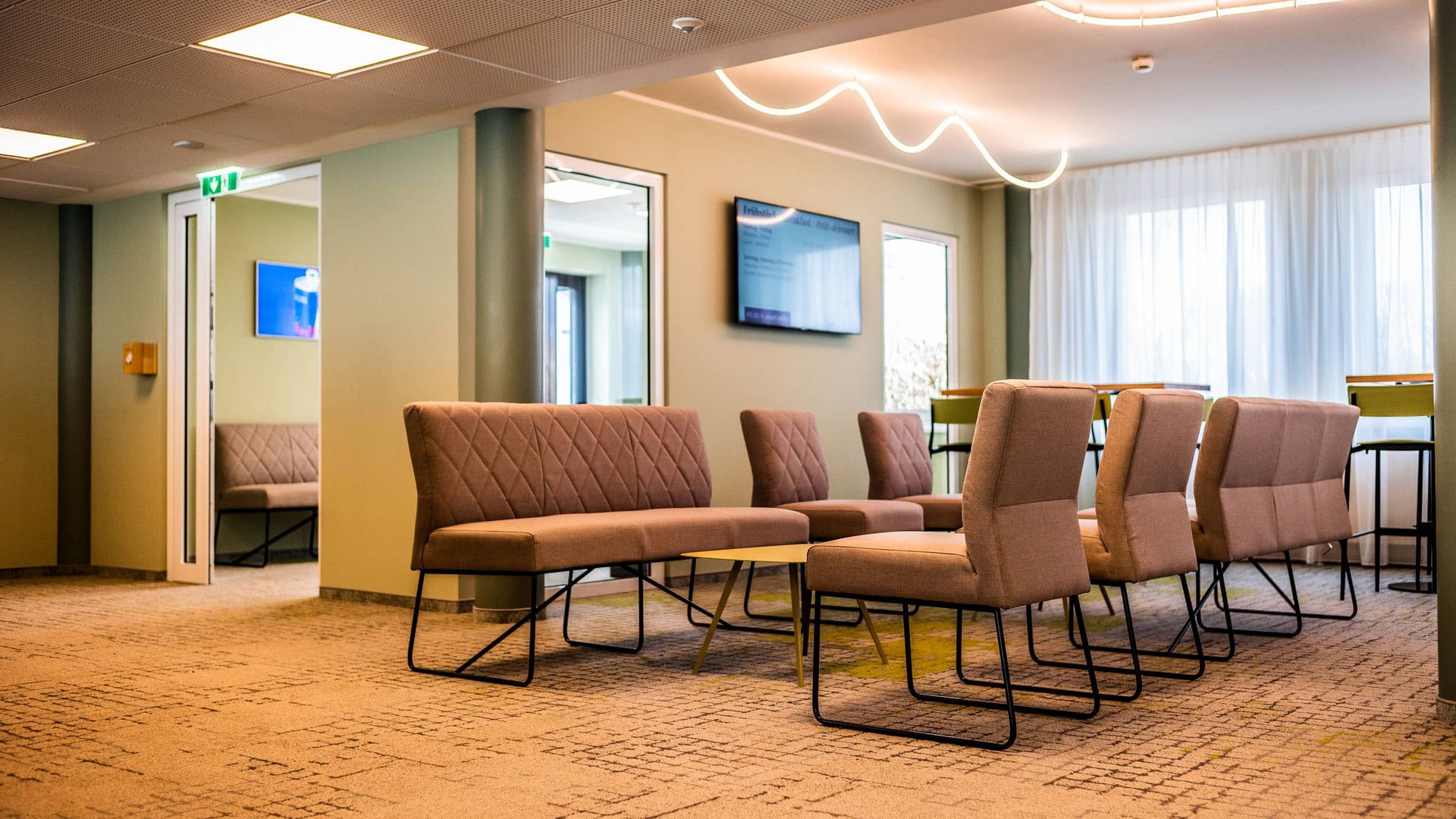 Modern waiting room with brown chairs and wall-mounted TV.