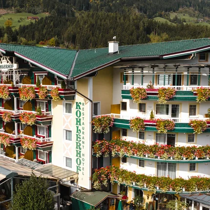 Hotel mit grünen Dächern und bunten Blumen an Balkonen in den Bergen