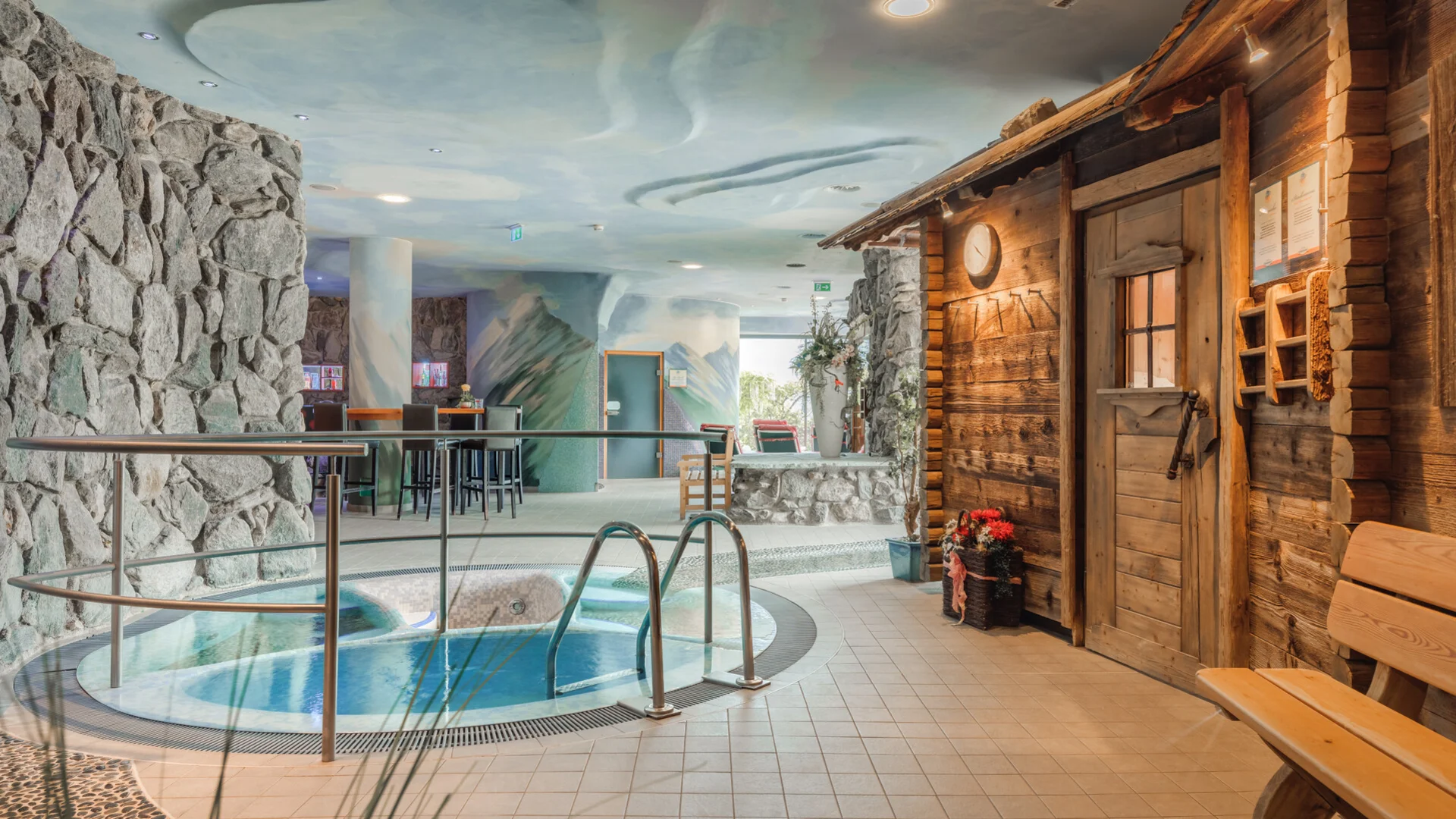 Innenansicht eines Wellnessbereichs mit Whirlpool und Holzhütte