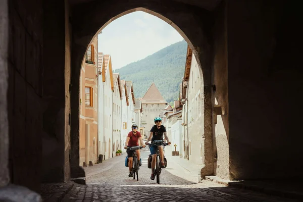 Radabenteuer am Reschensee © IDM Südtirol - Alex Moling Zwei Radfahrer fahren durch ein Tor in einer historischen Stadt