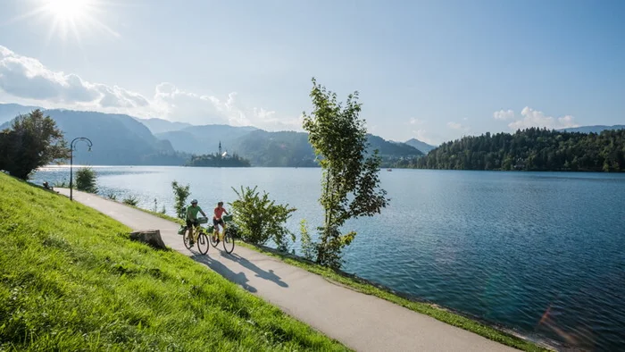 FunActive © FunActive Tours Two cyclists riding by a lake with mountains in the background