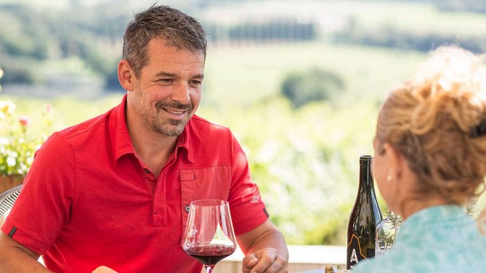 Paar genießt Pizza und Wein auf Terrasse mit Landschaft im Hintergrund
