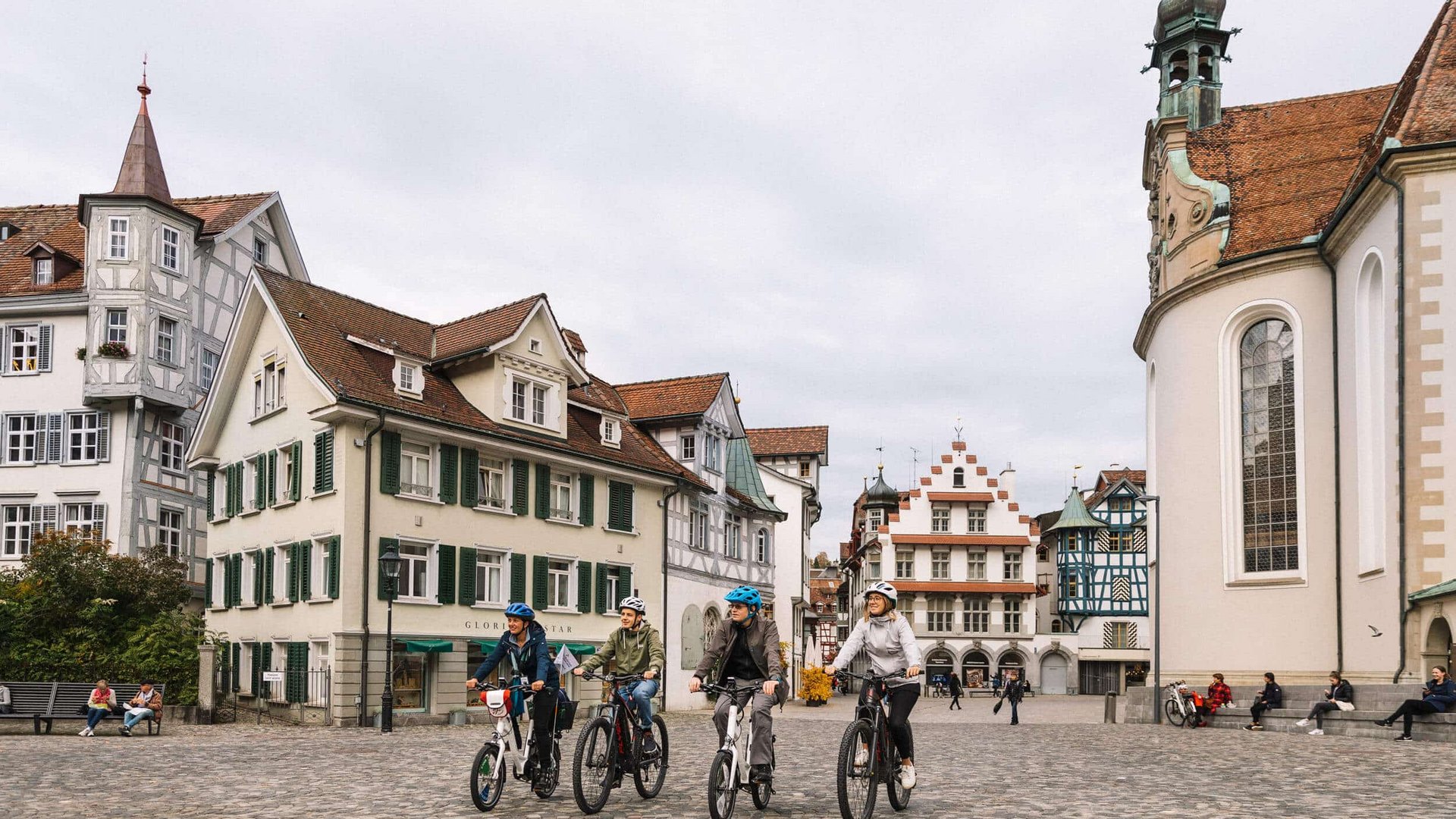 Vier Radfahrer in historischer Altstadt auf Kopfsteinpflaster unterwegs