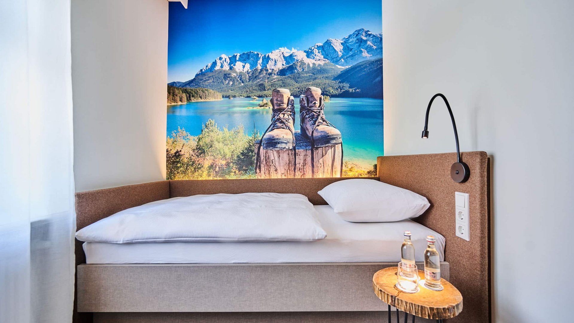 Single bed in modern room with mountain landscape and boots wall art