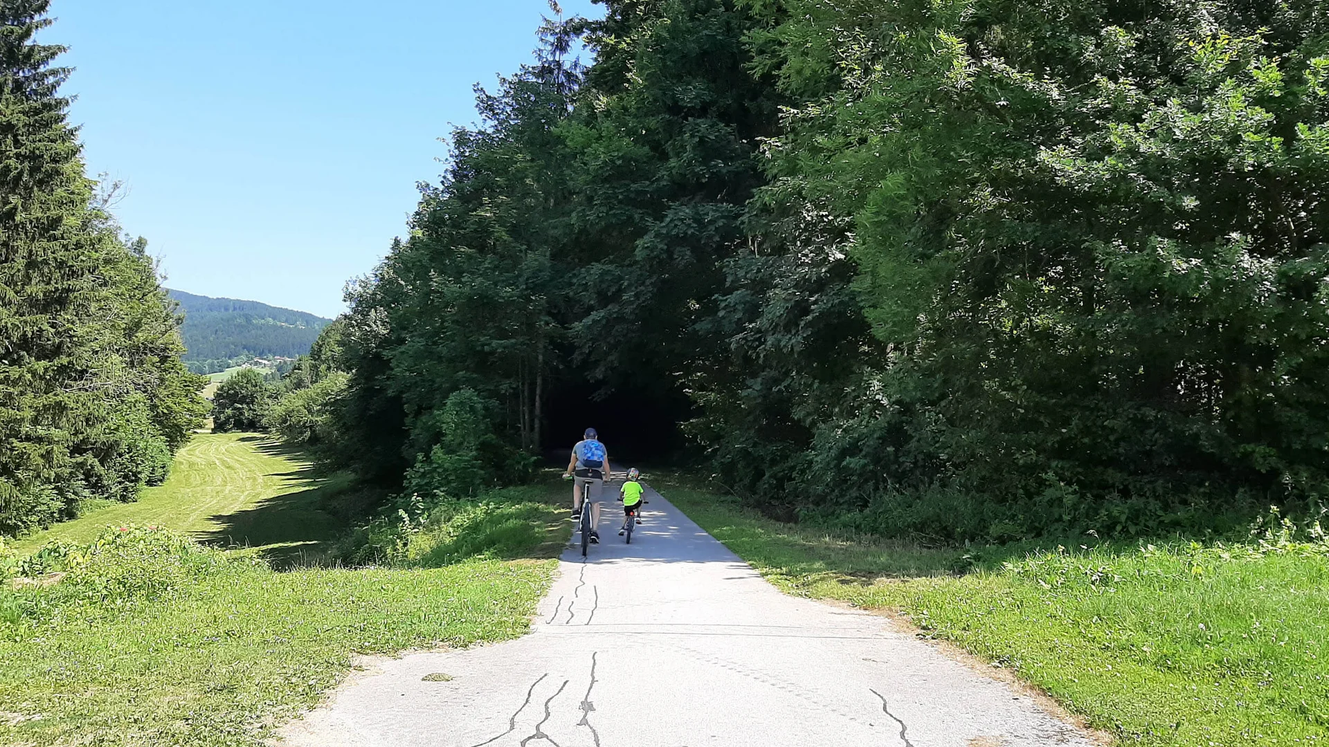 Volwassene en kind fietsen op pad door bebost landschap