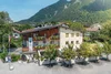 Collective enquiries © Isabella Anker Guesthouse with mountain backdrop and trees in sunny valley