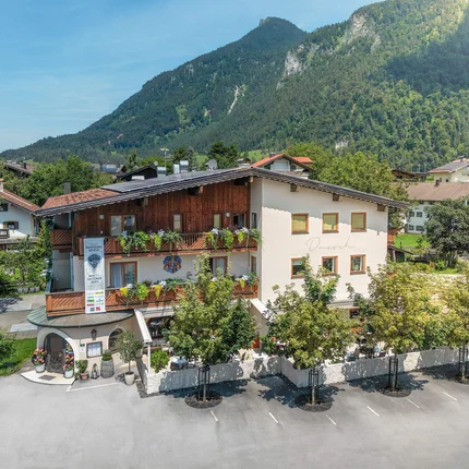 Gasthaus vor bewaldetem Berg in sonnigem Tal