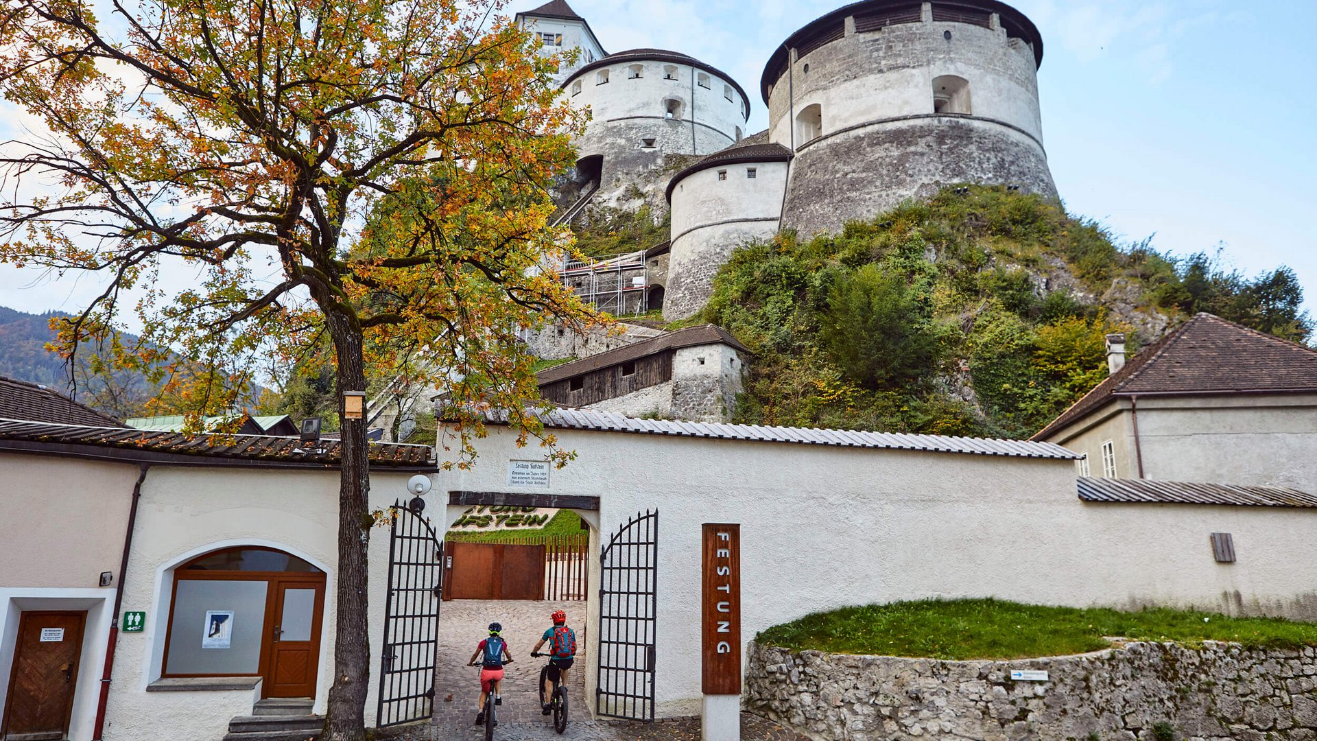 Cyclists entering a medieval castle with round towers